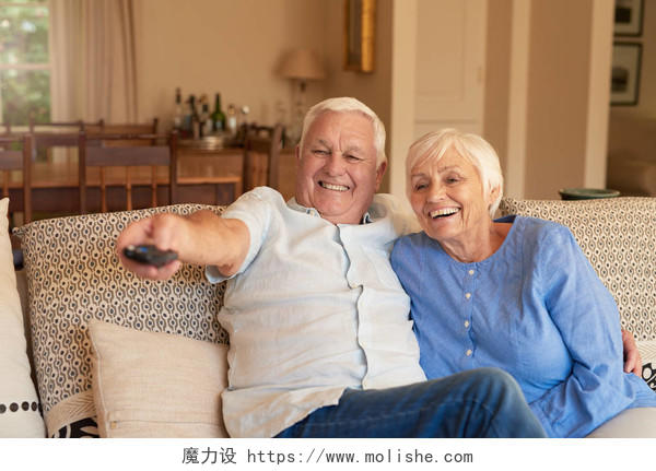老人与他的妻子坐在他们一起看电视的客厅里的沙发上微笑的老人